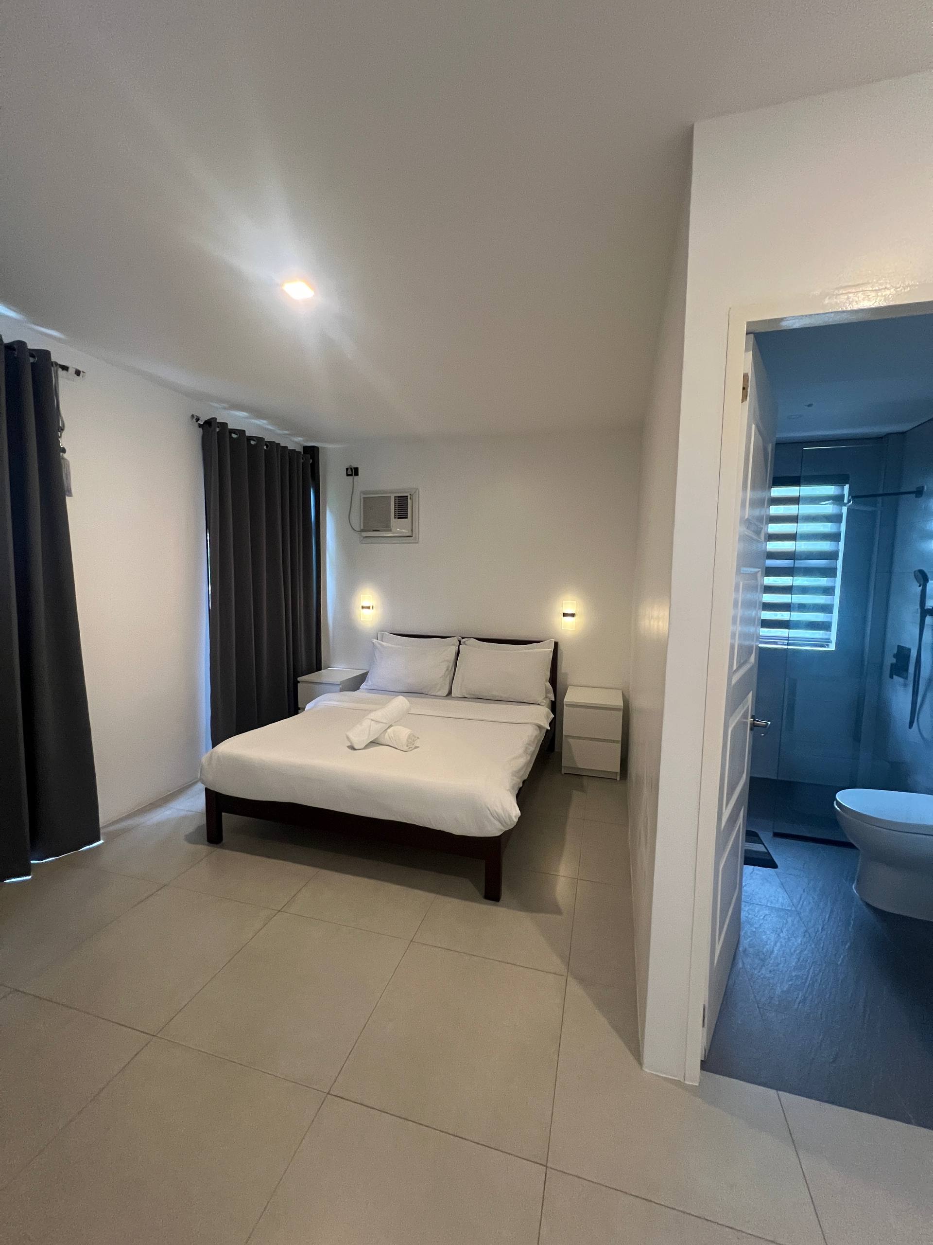 Bedroom 2 with queen bed, white linens and open doorway to en-suite