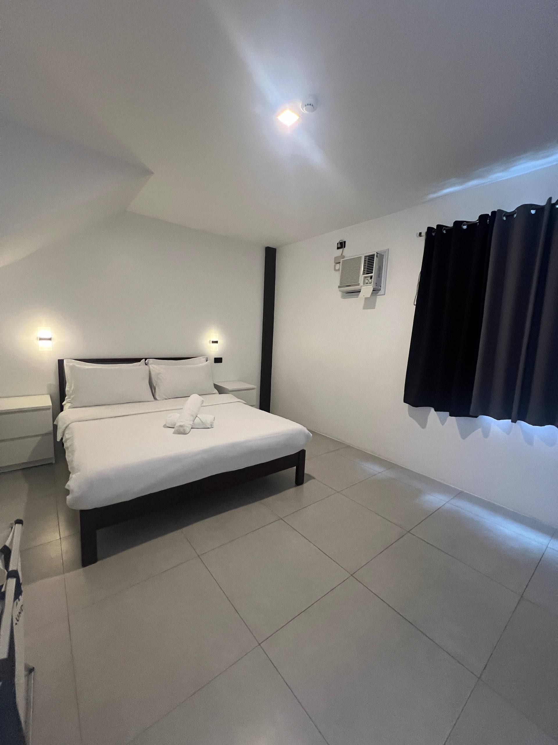 Bedroom 3 with slanted ceiling, queen bed and warm sconces