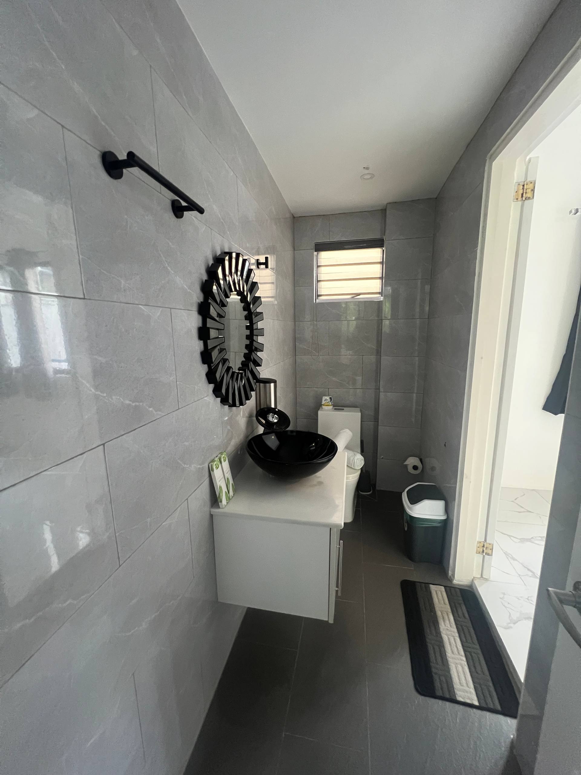 En-suite powder room with sunburst mirror, black sink and vanity
