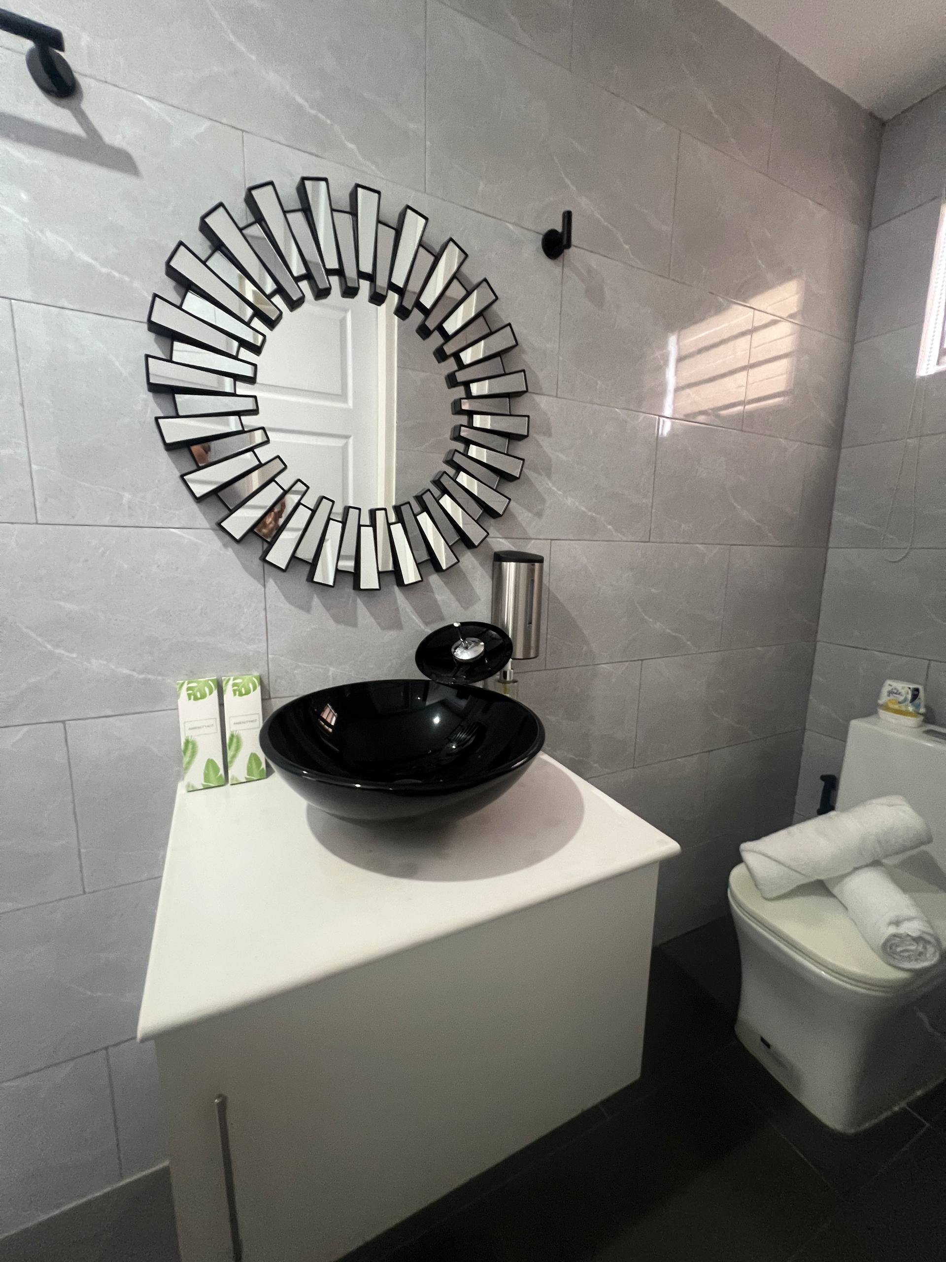 En-suite black vessel sink, sunburst mirror and toilet