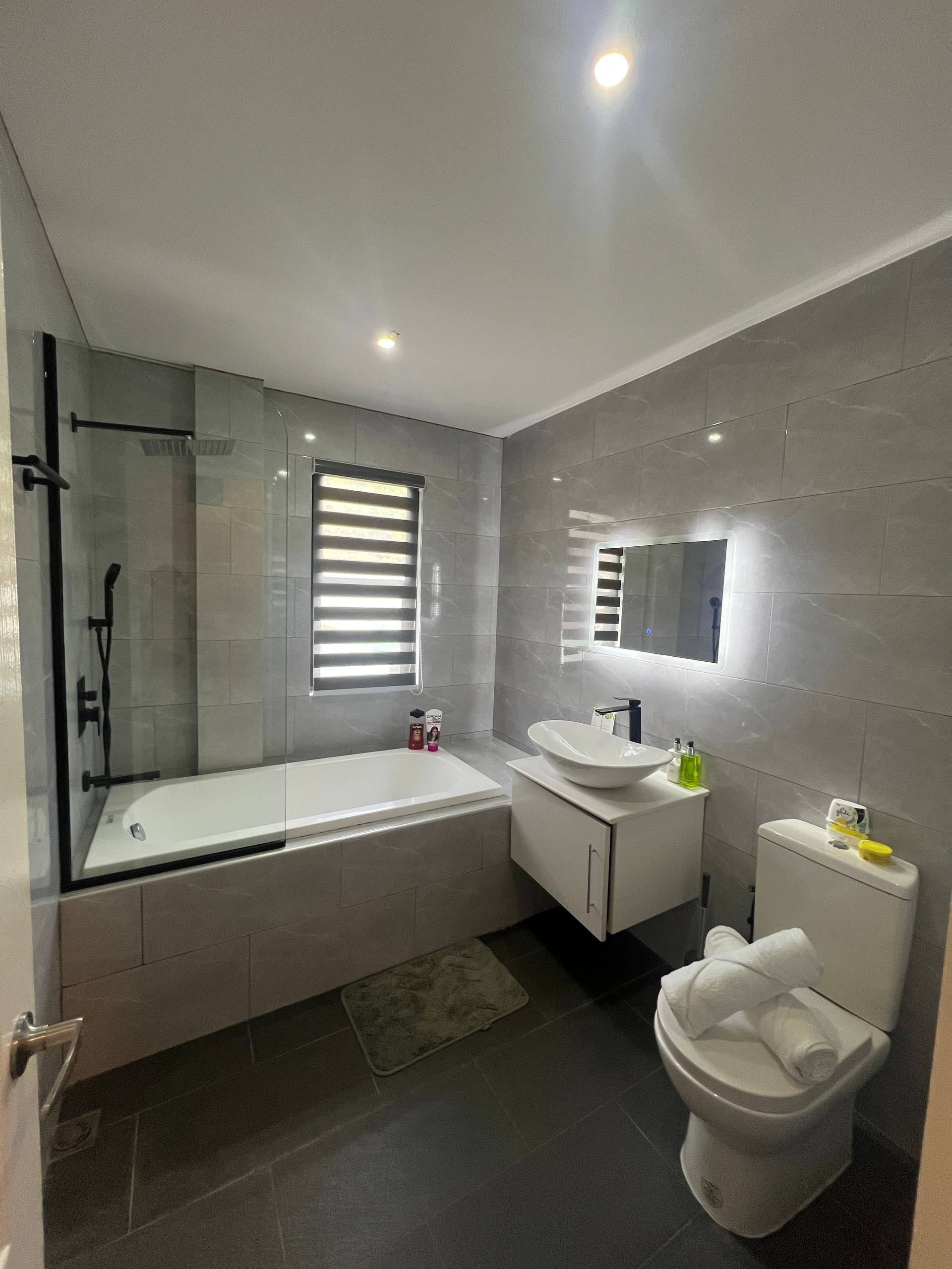En-suite bathtub with rainfall shower and vanity